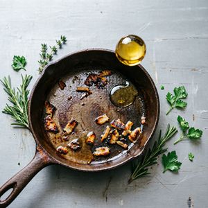 Qwen Image 2 output for the prompt: Overhead flat lay of a chef's station mid-service: cast iron pan, scattered herbs, a splatter of olive oil frozen mid-air