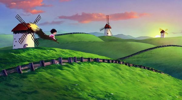 Wan v2.2 output for the prompt: Studio Ghibli style hand-drawn animation: a young girl flying on a broom over rolling green hills with windmills at sunset, hair blowing in the wind.
