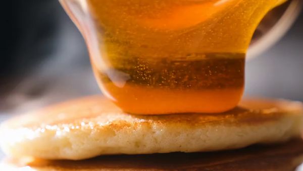 Mochi output for the prompt: A slow-motion close-up of honey being poured from a glass jar onto warm pancakes, light catching the viscous drip, steam rising subtly. Handheld, shallow depth of field.