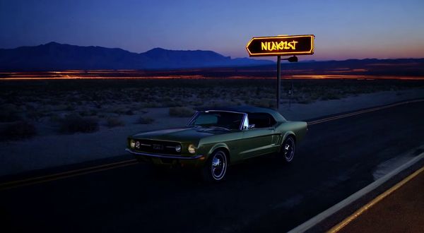 Wan v2.2 output for the prompt: Slow orbit around a 1965 Mustang convertible parked on a Nevada desert highway at twilight. Neon motel sign blinking in the background. Cinematic widescreen.