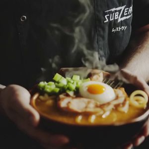 "Replace the food in the bowl with a steaming bowl of traditional Japanese ramen, filled with curly noodles, rich broth, slices of pork, boiled egg halves, seaweed, and fresh green onions, making it look warm, flavorful, and inviting.