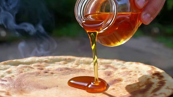SeeDance 1.0 Lite output for the prompt: A slow-motion close-up of honey being poured from a glass jar onto warm pancakes, light catching the viscous drip, steam rising subtly. Handheld, shallow depth of field.