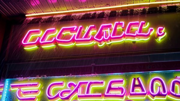 Kling 1.6 Pro output for the prompt: Extreme close-up of a neon diner sign flickering on that reads "NIGHT OWL — 24 HRS" in pink and yellow tubes, rain streaming down the glass behind it. 1990s aesthetic.
