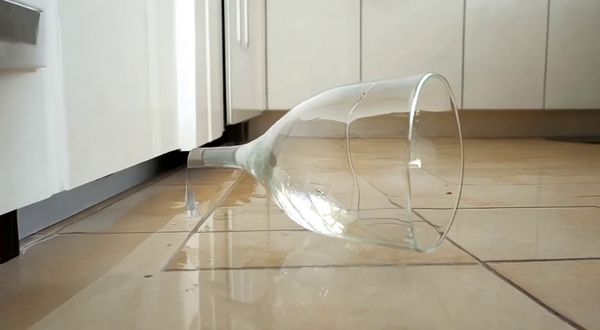 Wan v2.2 output for the prompt: A ripe red apple falls from a kitchen countertop and shatters a wine glass on the tile floor below. Shards scatter, juice splashes. 24fps, natural morning light.