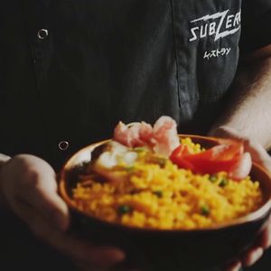 Replace the food in the bowl with a traditional Spanish paella, filled with saffron rice, shrimp, clams, and colorful vegetables, making it look vibrant and appetizing.