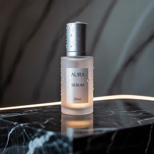 Ideogram V3 output for the prompt: Premium skincare bottle on a black marble surface, water droplets, soft rim light, label reads "AURA Serum 30ml"