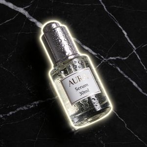 Seedream 4.5 output for the prompt: Premium skincare bottle on a black marble surface, water droplets, soft rim light, label reads "AURA Serum 30ml"