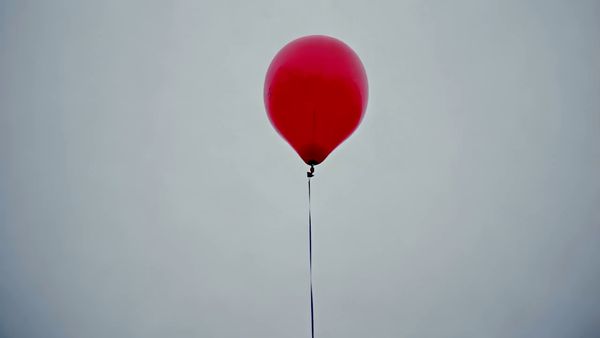 Minimax output for the prompt: A single red balloon rises slowly against a plain overcast grey sky. Nothing else in the frame. 4 seconds.