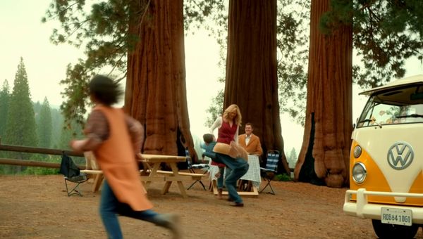 Luma Ray 2 output for the prompt: Super 16mm film grain, Kodachrome color: a family of four having a picnic in a yellow VW bus parked by a redwood forest. Children laughing, mom pouring lemonade.