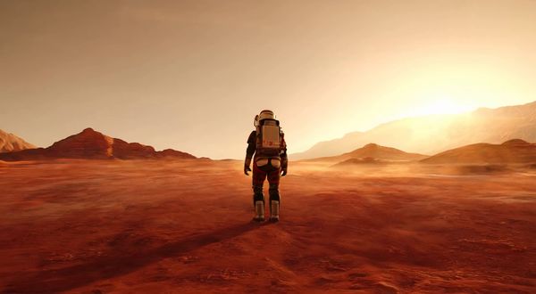 Wan v2.2 output for the prompt: A single astronaut stands on a red Martian plain with their back to the camera. The camera dollies forward slowly over 4 seconds. Dust devils swirl in the distance. Sunset lighting.
